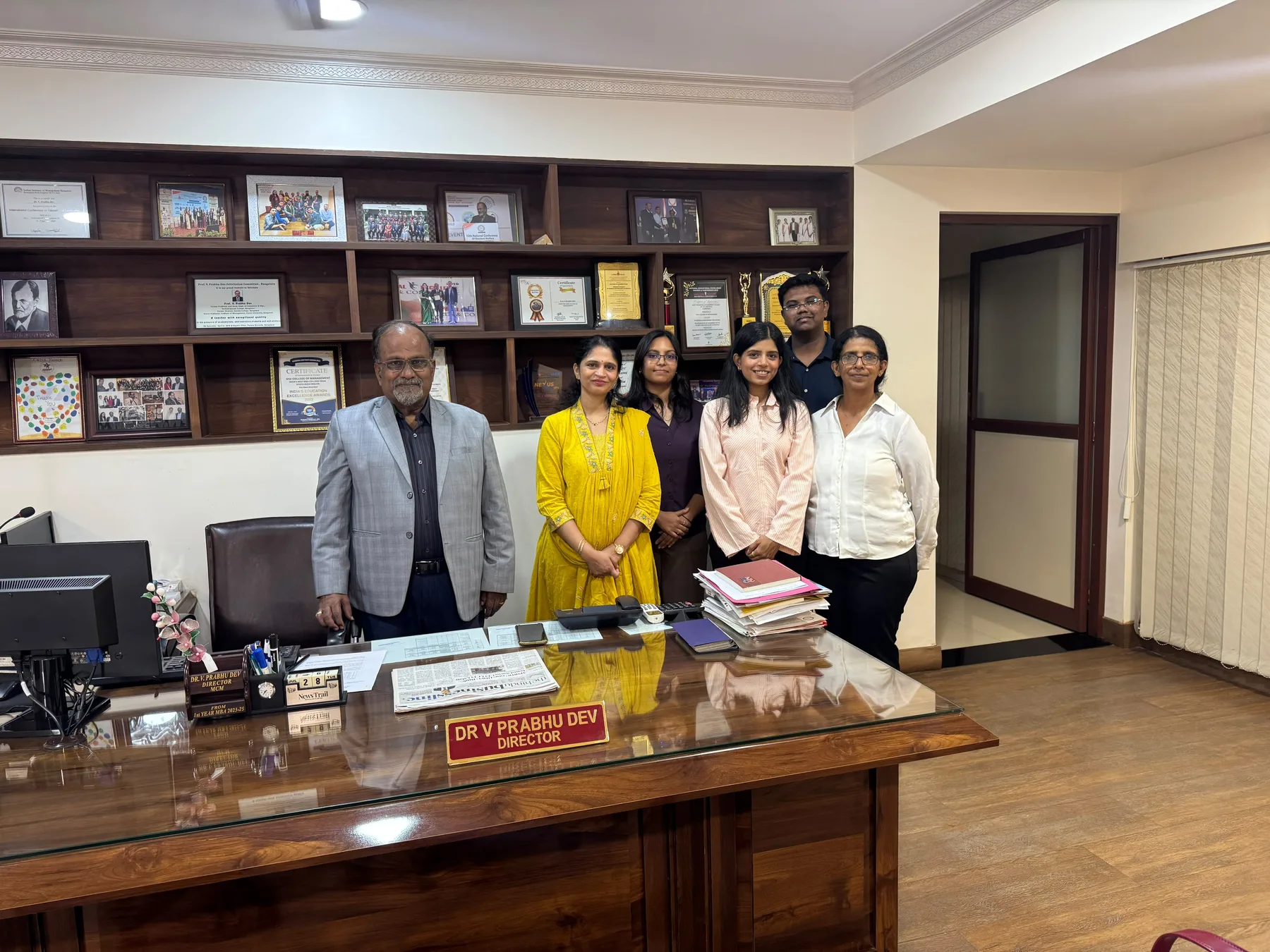 Dr. Aruna during a professional visit with a display of recognitions and awards in the background